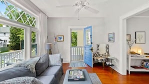 Un salon spacieux avec un canapé gris, une table basse et une porte bleue donnant sur un espace extérieur.