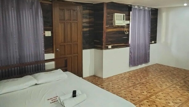 Una habitación de hotel con una cama, una puerta de madera, un equipo de aire acondicionado y suelo estampado.
