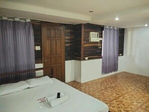 A hotel room with a bed, a wooden door, an air conditioning unit, and patterned flooring. - WJV INN SAN CARLOS II (Lapu-Lapu)