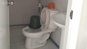 Un baño pequeño y funcional con inodoro, lavamanos y ducha.