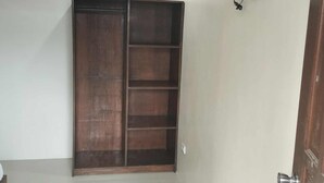 Una habitación con un armario de madera, un televisor de pantalla plana montado en la pared y una puerta con picaporte plateado.