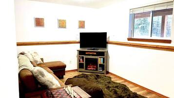Una sala de estar con chimenea, televisor y un tablero de ajedrez.
