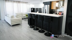 Une cuisine moderne avec un coin bar, un canapé et une table à manger.