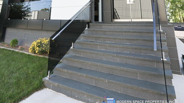 Un immeuble à plusieurs étages, doté d’un design moderne, qui présente une combinaison de façades en verre et de panneaux en bois, ainsi qu’un escalier menant à l’entrée.