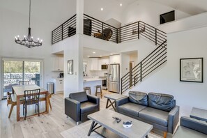 A spacious living area with a high ceiling, a dining table, sofas, and a kitchen in the background. - Luxe, New-Build Sturgis Retreat w/ Mountain Views (Sturgis)