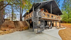 A two-story cabin with a spiral staircase, outdoor seating, and a view of the surrounding forest. - Remodeled Cabin: Golf & Hot Springs (Garden Valley)