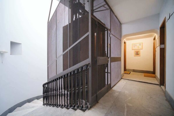 A modern interior with a staircase, a wall-mounted screen, and a hallway leading to a door.