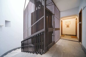 A modern interior with a staircase, a wall-mounted screen, and a hallway leading to a door.
