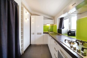 Una cocina moderna con armarios blancos, encimera negra y salpicadero verde.