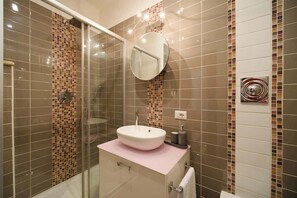 A modern bathroom with a glass shower enclosure, a white sink, and a mirror. - BuddyRent - Elinor's Refuge - Flaminio - 3 (roma)