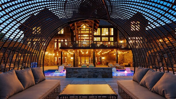 Un espacio lounge al aire libre con piscina, asientos y un porche cubierto.