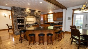 Una cocina amplia con una isla de piedra, taburetes de bar de madera y un comedor con una gran mesa de madera y sillas.