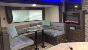A compact living space with a sofa, a small table, and a TV. - The GreyWolf - Convenient & Cozy RV (Mobile)