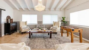 A spacious living room with a high ceiling, a chandelier, a sofa set, a coffee table, and a foosball table. - Hillside Hideaway - Private Woodland Hills Canyon Guest Suite with Views (Los Angeles)