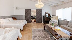 A bedroom with two beds, a wooden bench, a table with a plant, and a large window. - Hillside Hideaway - Private Woodland Hills Canyon Guest Suite with Views (Los Angeles)
