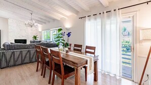 A dining area with a wooden table and chairs, a grey sofa, and a chandelier. - Hillside Hideaway - Private Woodland Hills Canyon Guest Suite with Views (Los Angeles)