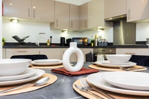 A modern kitchen with white cabinets, a black countertop, and a central white vase.