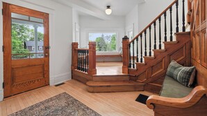 A wooden staircase with a bench at the top, a wooden door, and a view through a window.