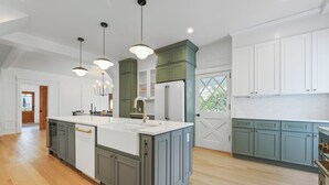 A spacious kitchen with a large island, white cabinetry, and green accents.