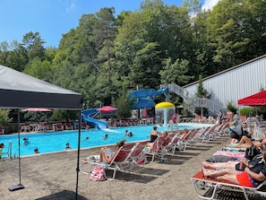 A pool area with lounge chairs, a water slide, and a covered seating area. - Charming 1-bedroom condo in serene Clymer with multiple amenities (Clymer)