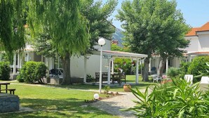 Un espace extérieur abrité, doté d’une pergola, d’un barbecue et d’un panneau indiquant une issue de secours en cas d’incendie.