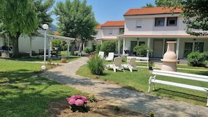 A courtyard with a paved path, outdoor seating, and a building with a red-tiled roof.