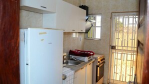 Una cucina compatta con mobili bianchi, forno integrato e una finestra con inferriate.