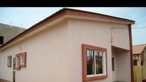 Un edificio a un piano con tetto piatto, un piccolo portico e una finestra con cornice bianca.