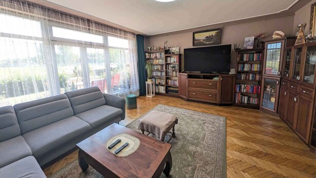 Een woonkamer met een bank, salontafel, televisie en boekenkasten.
