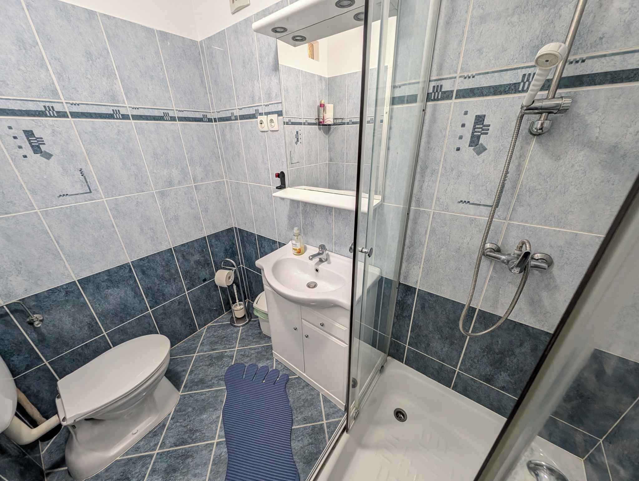 A bathroom with a toilet, sink, and shower.