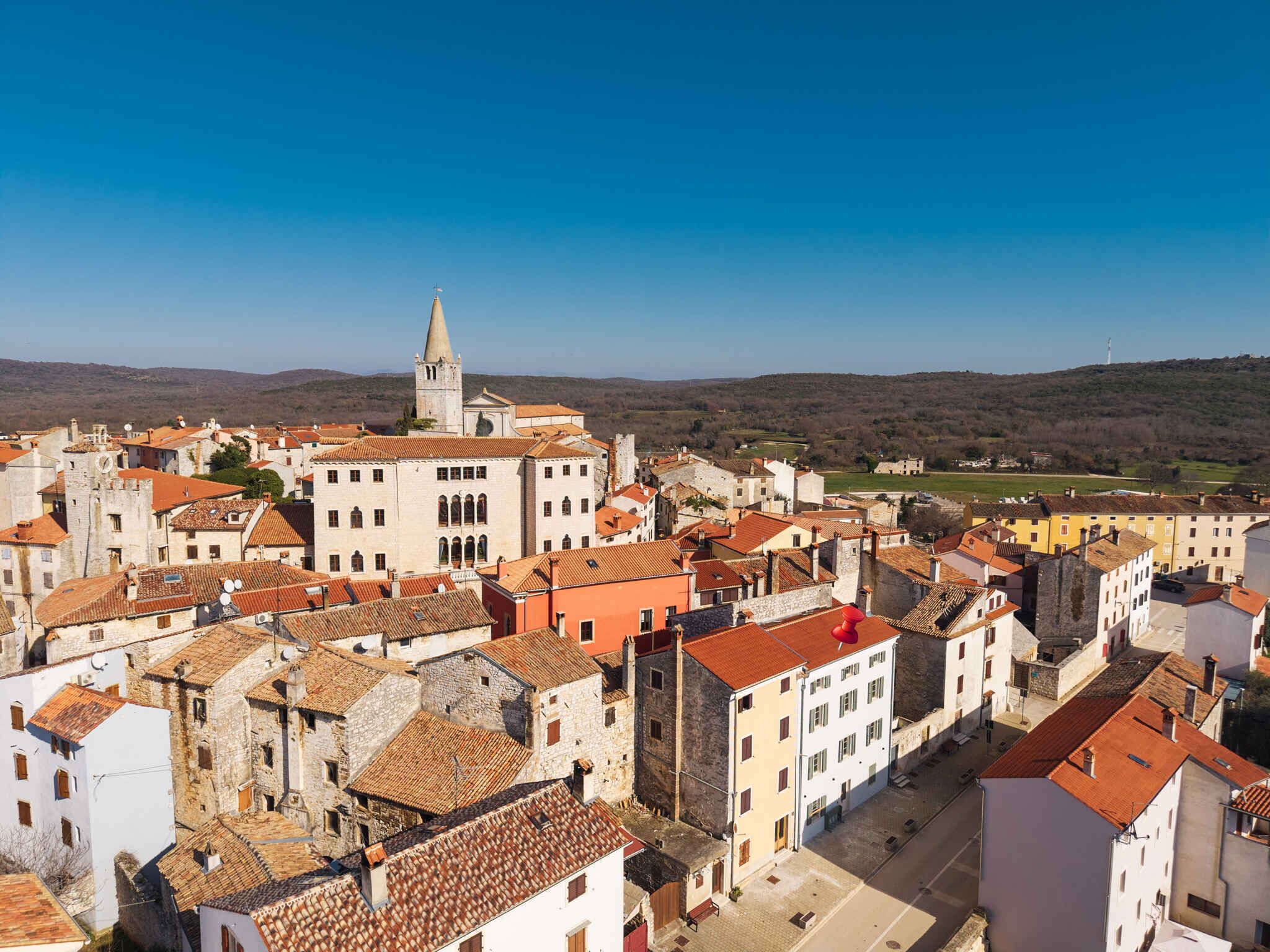 Une ville historique, avec une église remarquable et un clocher, entourée de bâtiments traditionnels aux toits de tuiles rouges.
