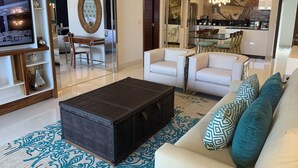 Een moderne woonkamer met een bank, fauteuils, een salontafel en een televisie.