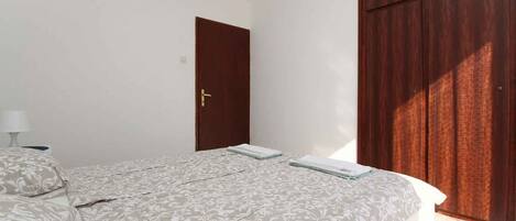 Ein Schlafzimmer mit einem Bett, einem Kleiderschrank und einer Tür.