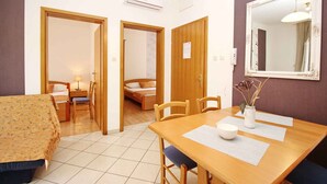 Ein Zimmer mit einem Bett, einem Schreibtisch und einem Stuhl. An der Wand hängt ein Spiegel und es gibt ein Fenster.