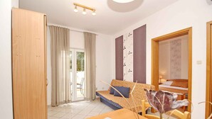 Ein modernes Wohnzimmer mit einer Couch, einem Esstisch mit einer Vase und einem Holzschrank.