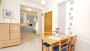 Un comedor con una mesa y sillas de madera, un mueble aparador y una cocina al fondo.