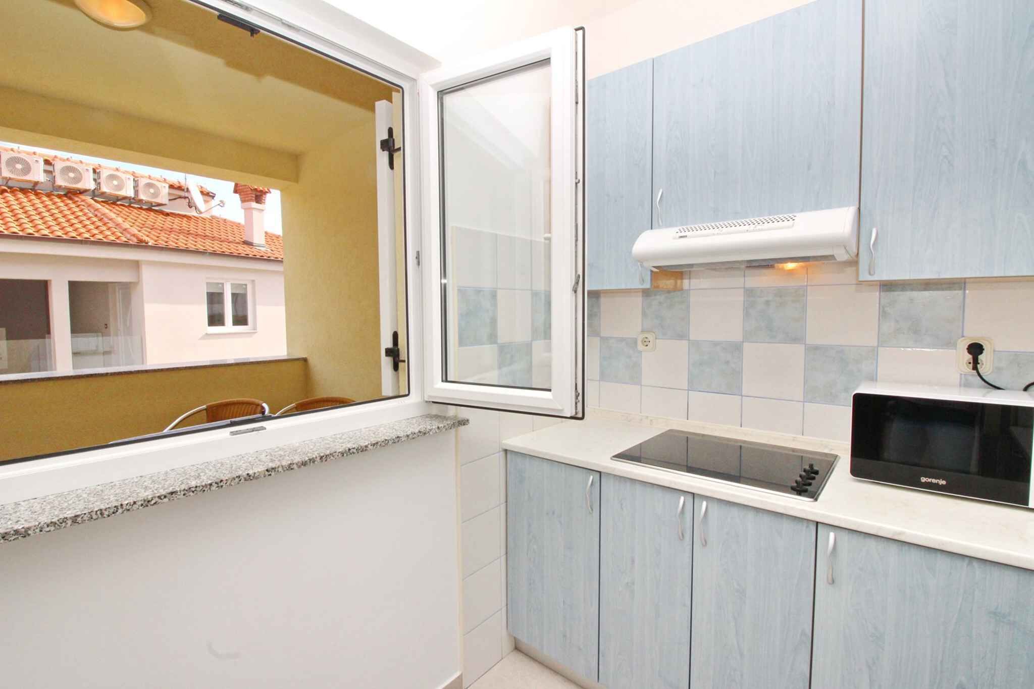 Una cocina con ventana, microondas y armarios azul claro.