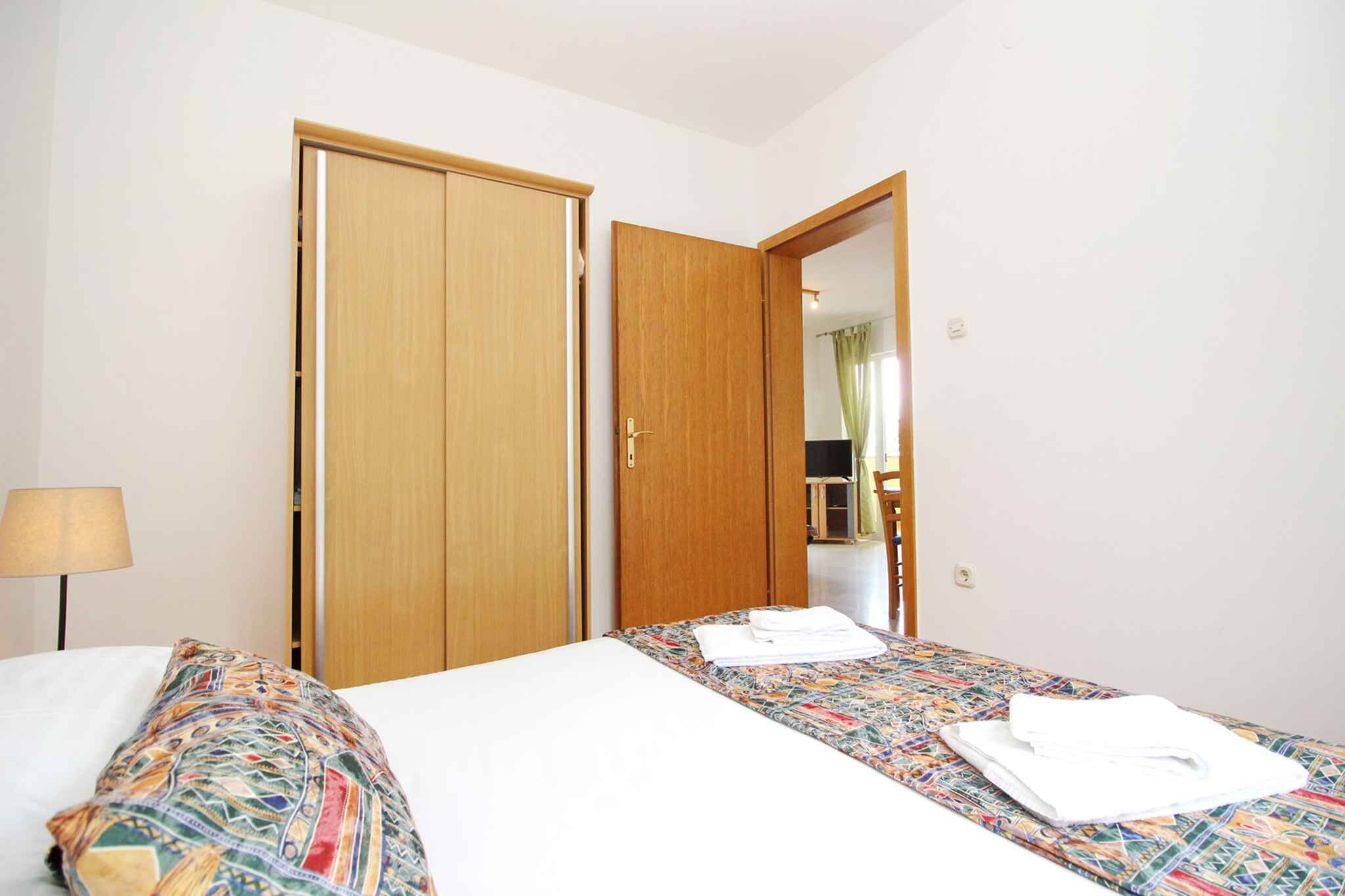 A hotel room with two beds, a wardrobe, and a mirror reflecting a bathroom.