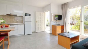 A modern kitchen with white cabinets, a built-in microwave, and a dining area with a table and chairs. - Holiday flat with terrace near the beach (Baška)
