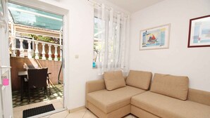 Ein beiges Ecksofa, ein Esstisch mit Stühlen und ein Fenster mit durchscheinenden Vorhängen.