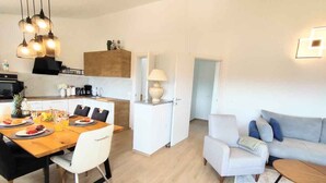 Ein modernes Wohnzimmer mit einer Couch, einem Couchtisch und einem Essbereich mit Tisch für zwei Personen.