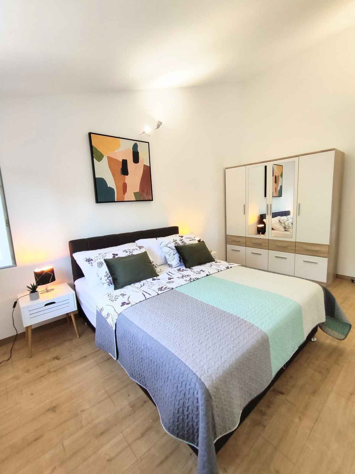 A bedroom with a bed, bedside tables, a wardrobe, and a painting on the wall.