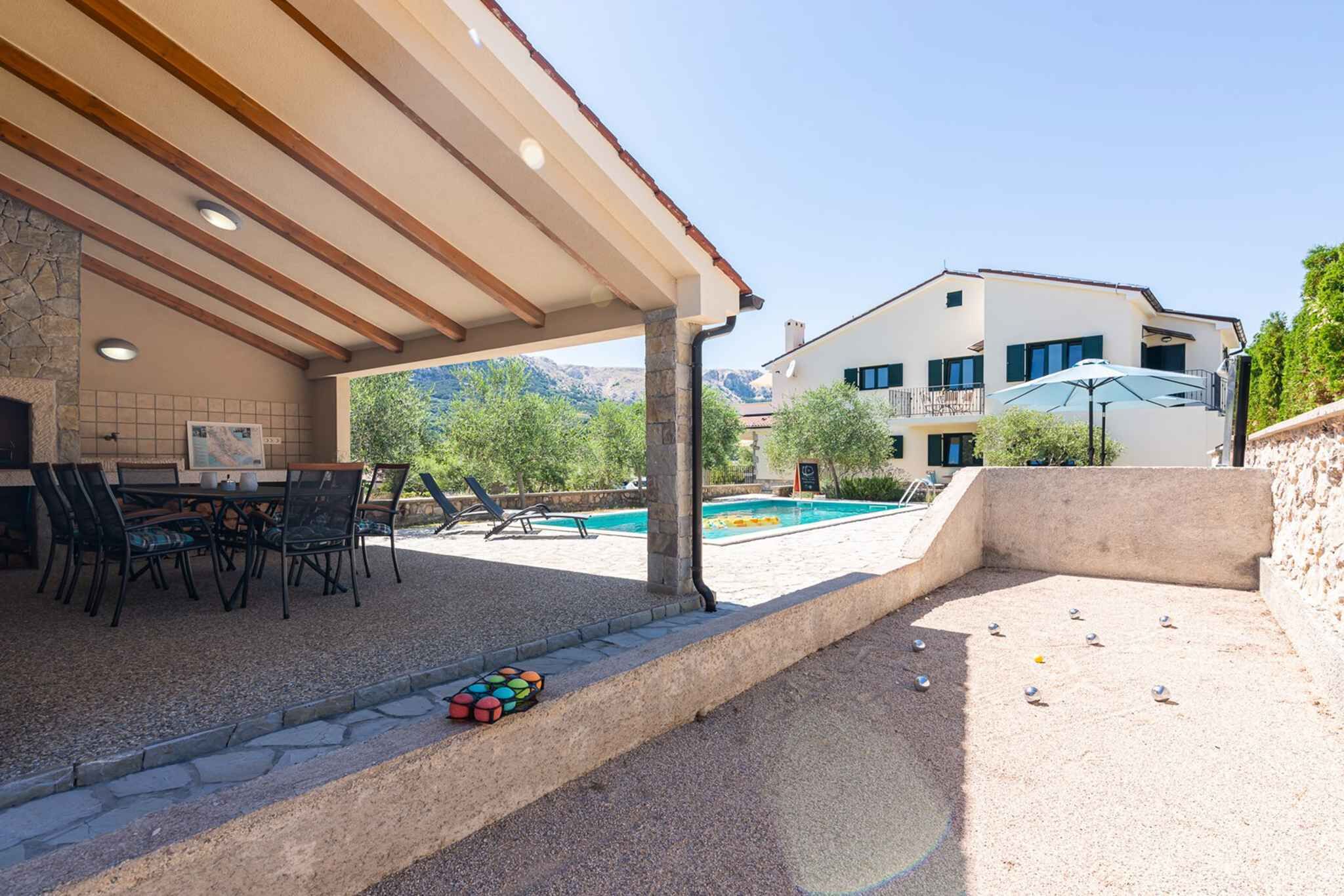 A covered outdoor area with a pool, seating, and a view of a mountain.