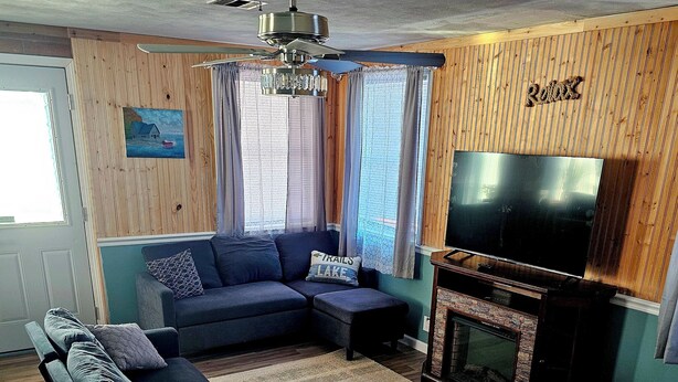 Una sala de estar con un sofá modular, una televisión y una chimenea.