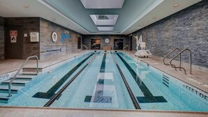 Ein Schwimmbecken mit deutlichen Bahnen, einem Rettungsschwimmerstuhl und einer Oberlichter.