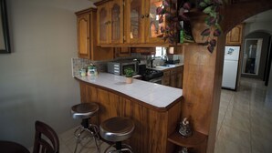 Een keuken met houten kastjes, een wit aanrecht en twee barkrukken.