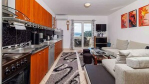 Una cocina moderna con armarios de madera, estufa y comedor con sofá y mesa.