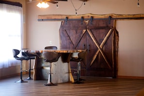 Un comedor con mesa y sillas de madera, una puerta rústica de granero y una lámpara colgante.
