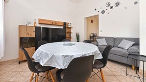 A dining area with a round table, chairs, and a wooden cabinet with a TV. - Holiday apartment with air conditioning and balcony (Valbandon)