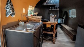 Une cuisine compacte comprenant un évier, une table en bois et des étagères remplies d’ustensiles de cuisine.
